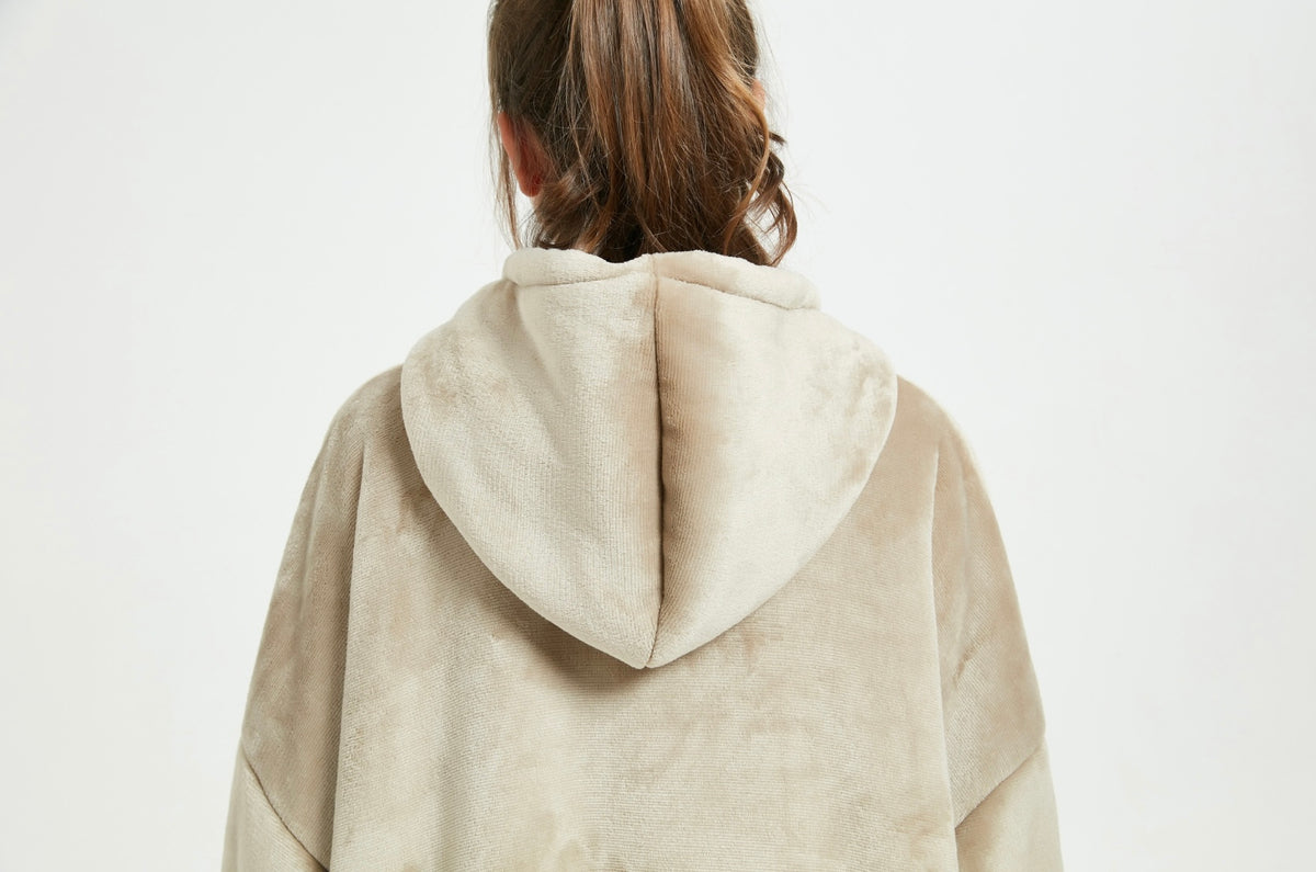 A back view of a beige Cozify plush wearable blanket hoodie, showcasing the smooth velvety fabric and relaxed oversized fit.