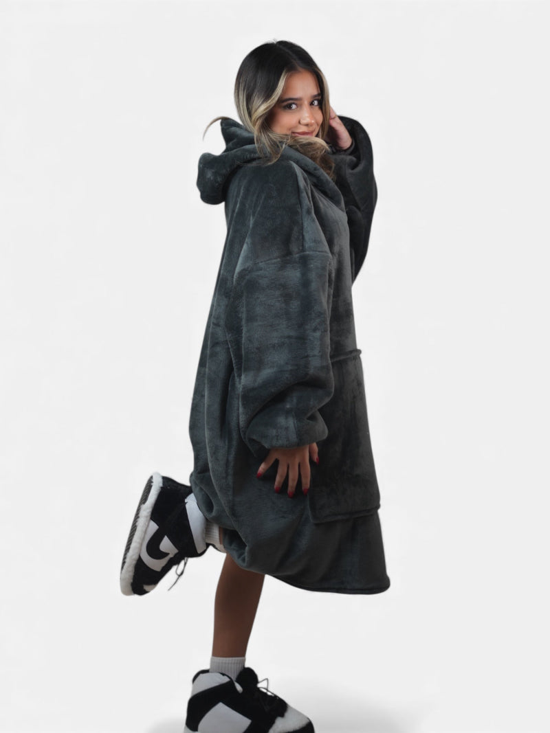 Cozify oversized wearable blanket hoodie in charcoal grey with a soft plush finish, shown from a side view on a woman wearing black and white slippers against a white background.