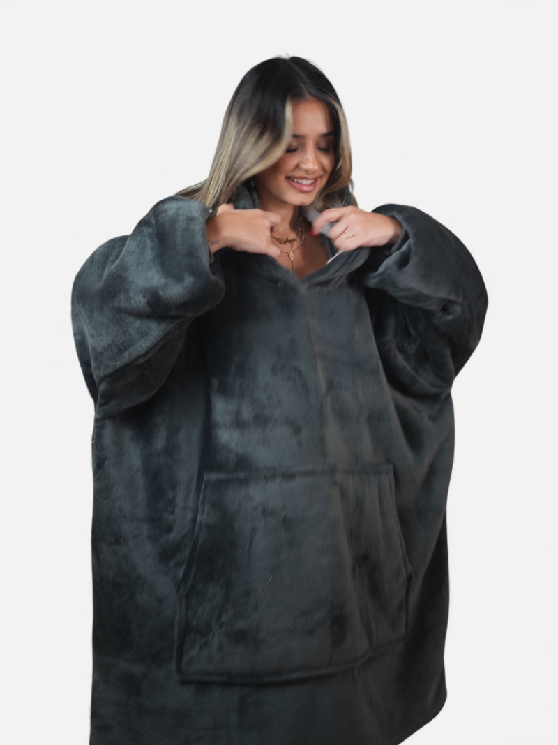 Close-up of a woman smiling while adjusting the collar of her charcoal gray oversized Cozify sherpa-lined hoodie blanket with large front pocket.