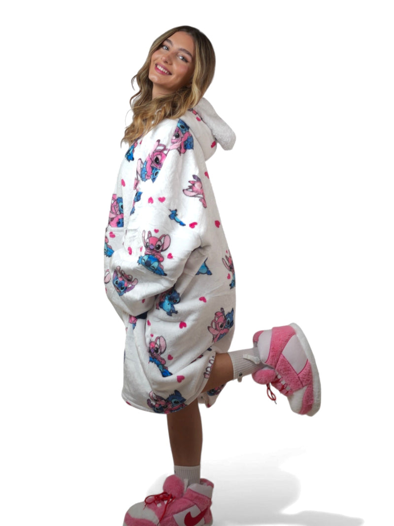 Woman wearing a white oversized Stitch and Angel hoodie blanket with sherpa lining and matching pink fuzzy slippers – cozy Disney-inspired loungewear set for women and teens, perfect for winter comfort and gifting in Lebanon